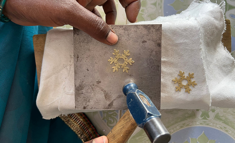 Hands of an artisan hammering brass jewellery