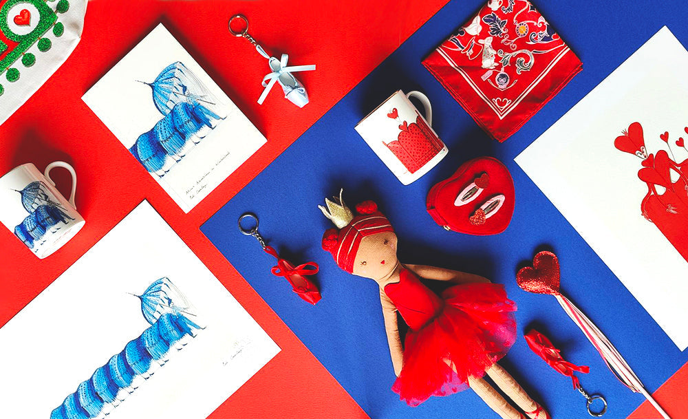 Flat lay on red and blue card of a selection of Alice products including ceramics, prints, keyrings, doll jewellery box and hair accessories