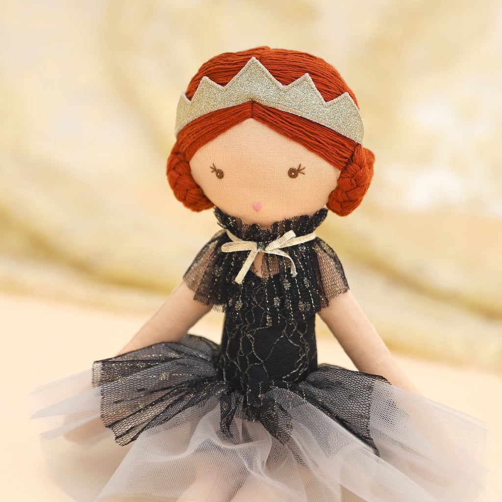 Close up of the Black Swan Doll with red hair and a black dress on a blurred background