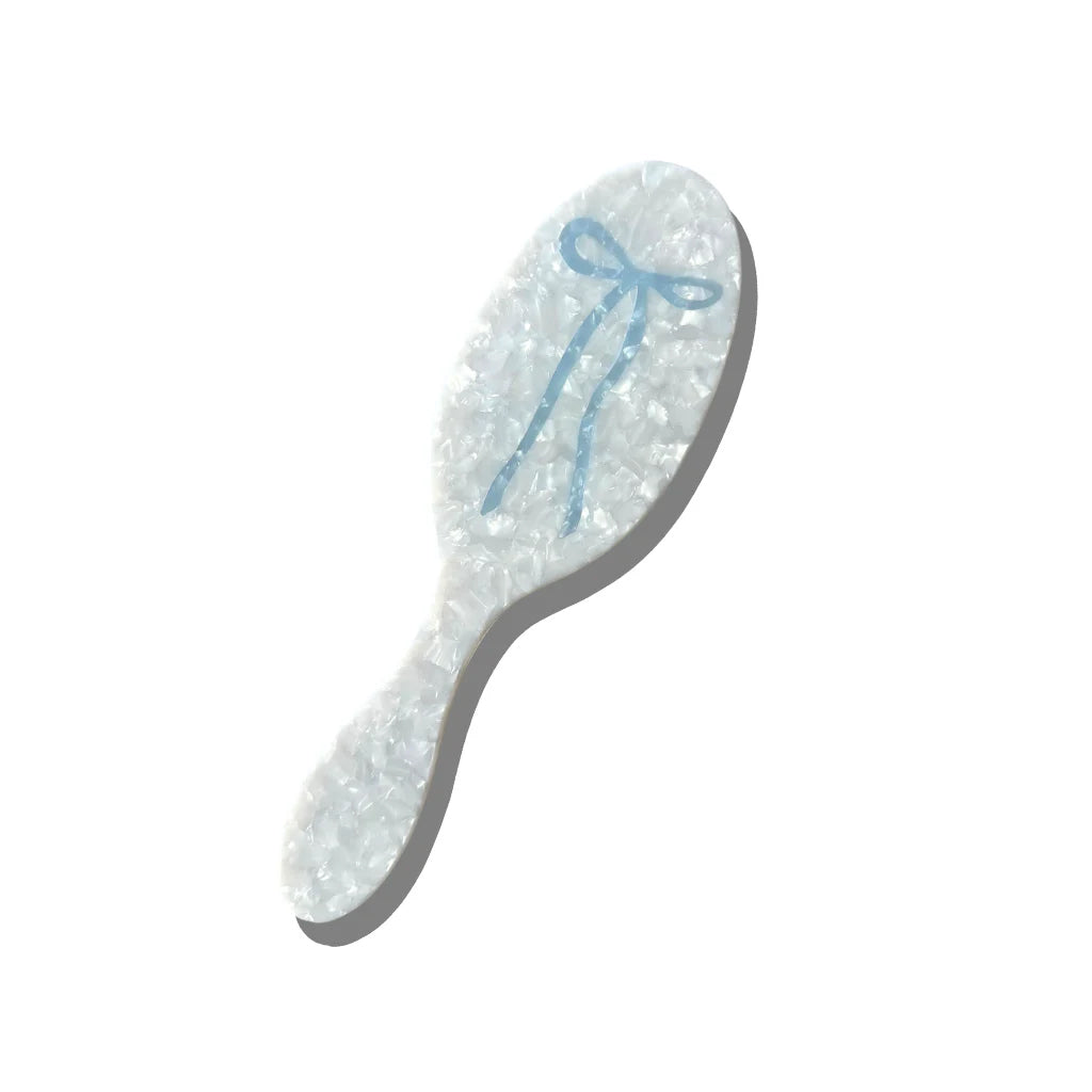 Decorative hairbrush with a blue ribbon on a white background