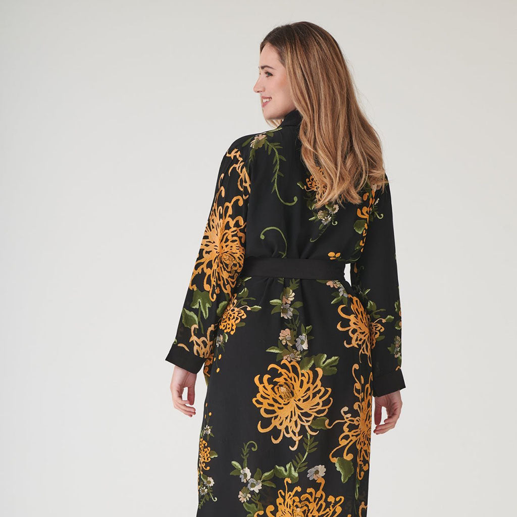 close up of a lady in a Black and gold floral dressing gown on a grey 
background