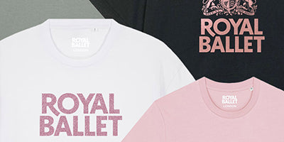 A selection of RBO T-shirts featuring the 'ROYAL BALLET' logo printed in pink. The shirts are shown in white, black, and light pink, arranged diagonally with the black shirt in the upper right corner.