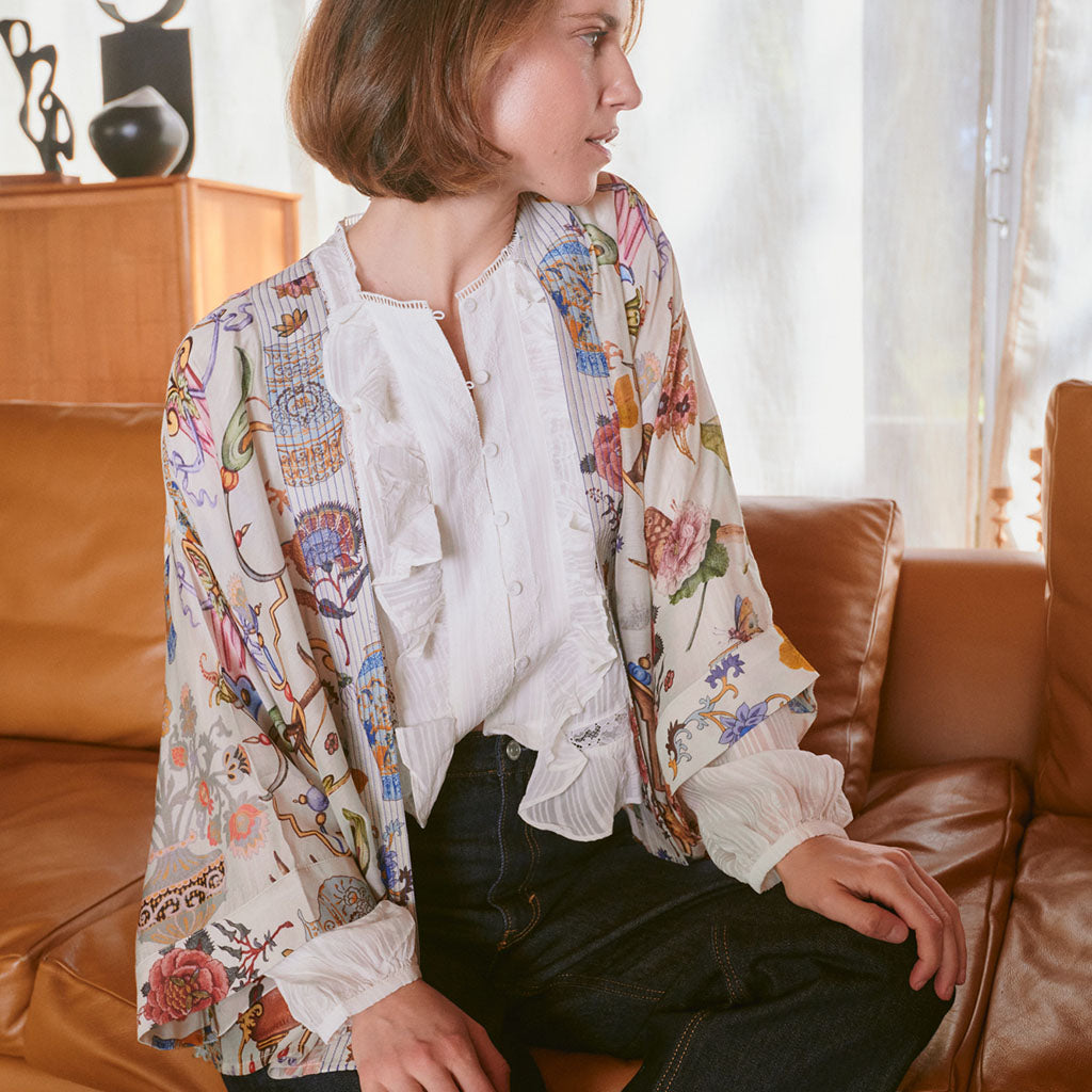Model wearing Cornucopia Kimono over white top and jeans on sofa
