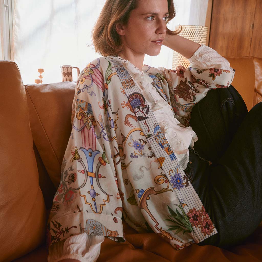 Model wearing Cornucopia Kimono on tan leather sofa