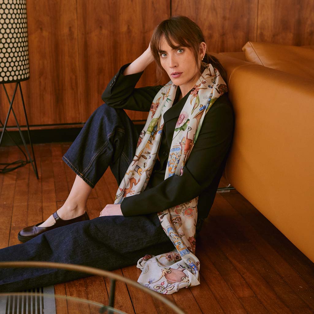 model wearing the Cornucopia Scarf sitting with her back to a tan sofa