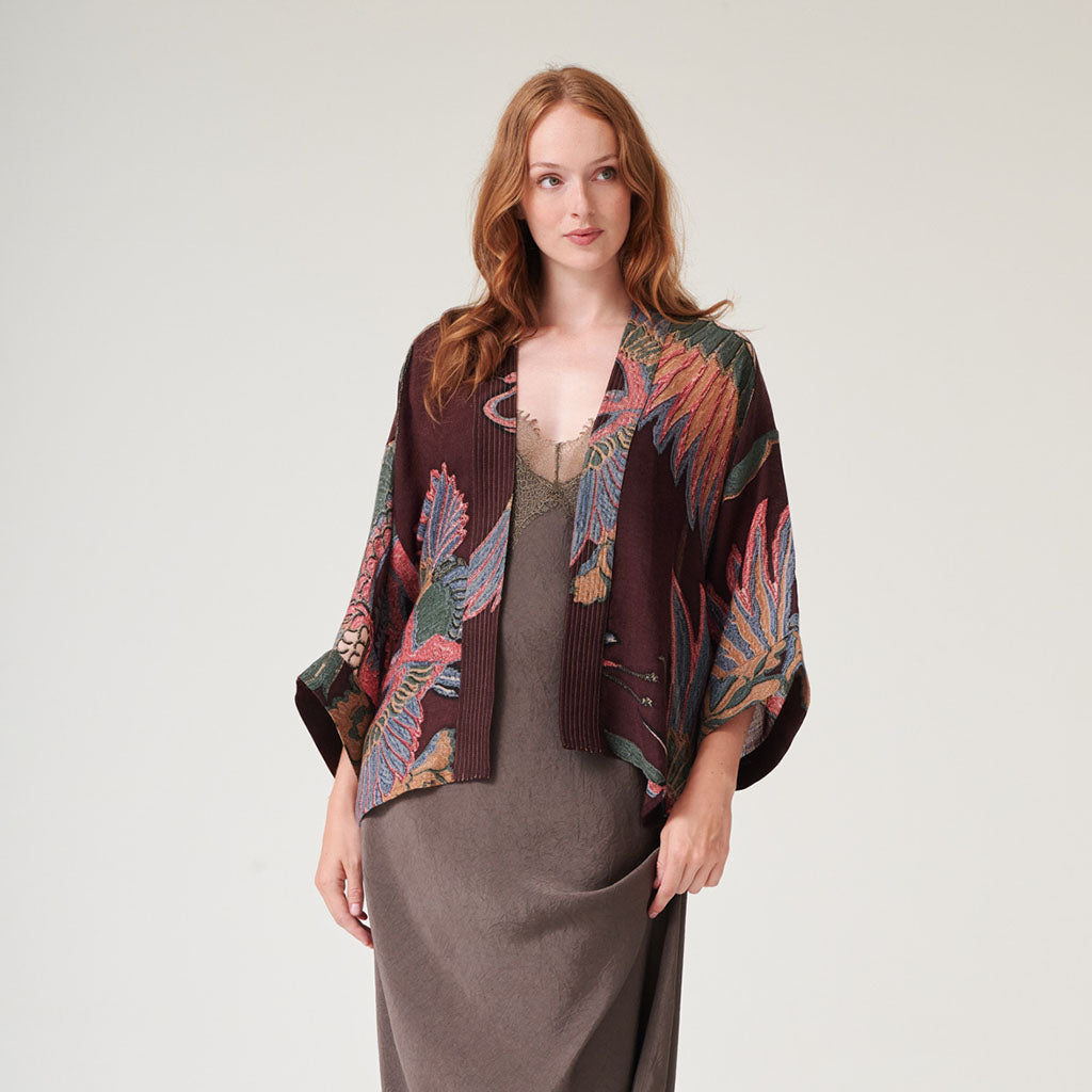 Colourful patterned wool kimono jacket on a hanger against a white background