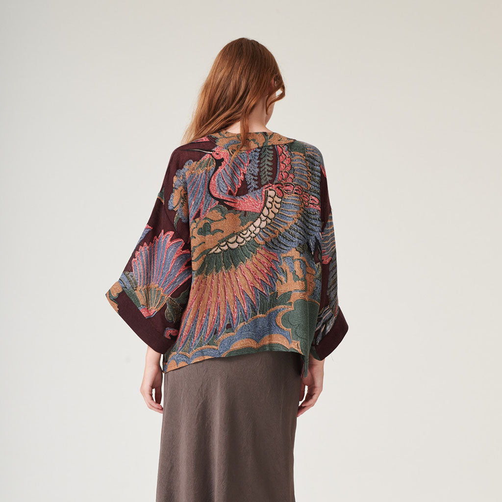 Woman wearing a patterned wool kimono jacket with a plain background