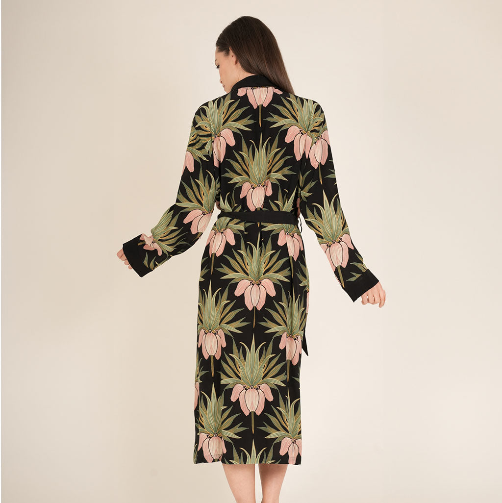 Woman wearing a dressing gown with an art deco floral pattern on a beige background