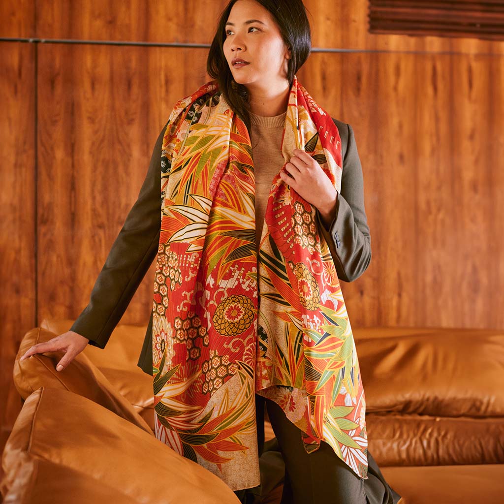 Model wearing the Fans Scarlet Scarf kneeling on a tan leather couch