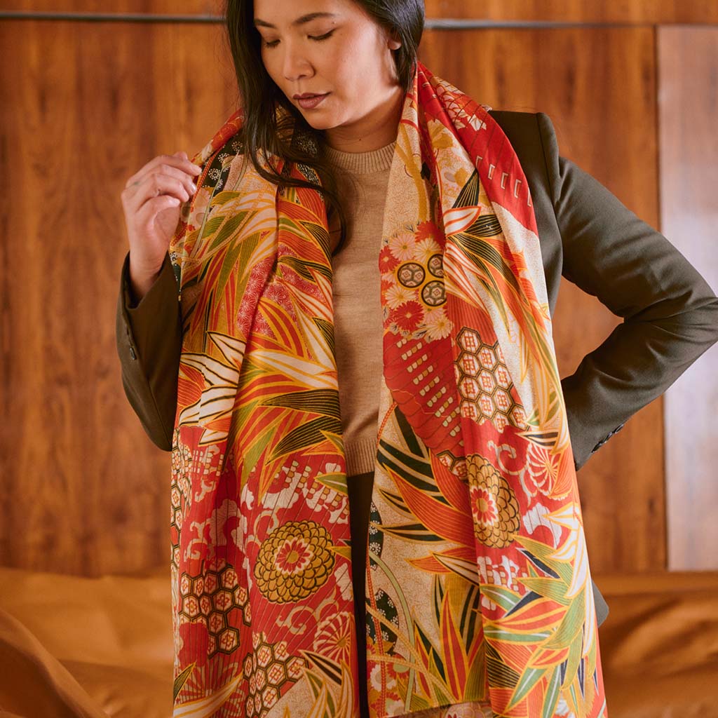 Close up of Model wearing the Fans Scarlet Scarf kneeling on a tan leather couch