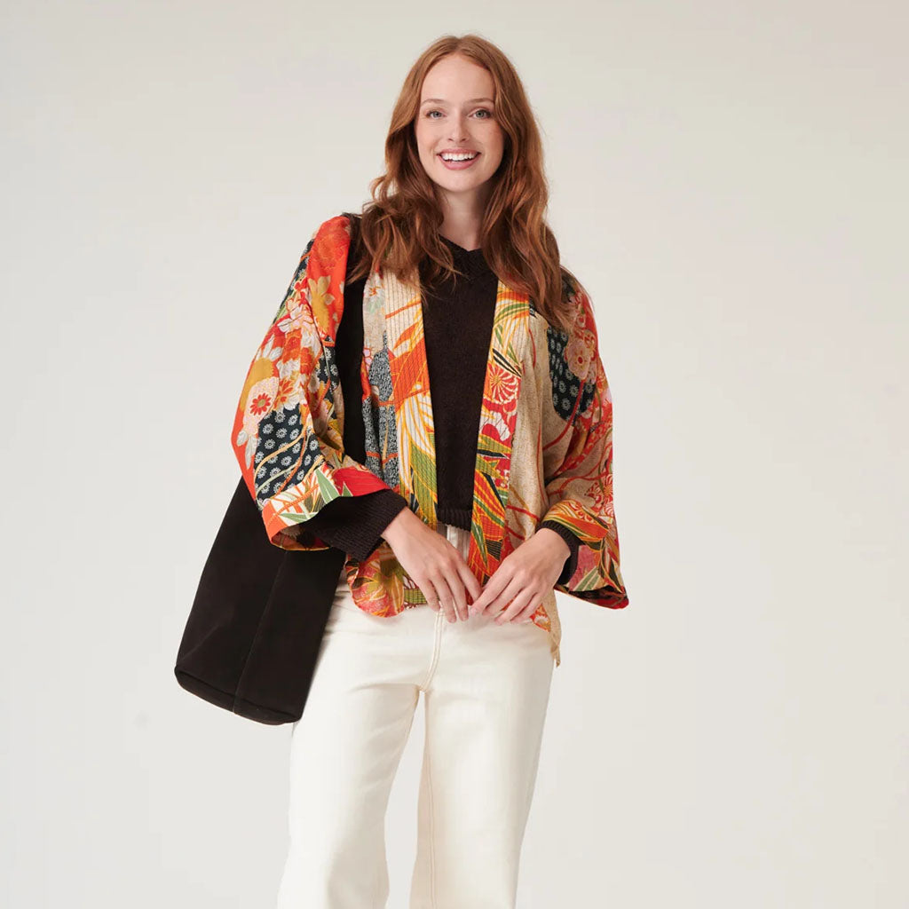 Woman wearing a colourful kimono-style jacket on a white background