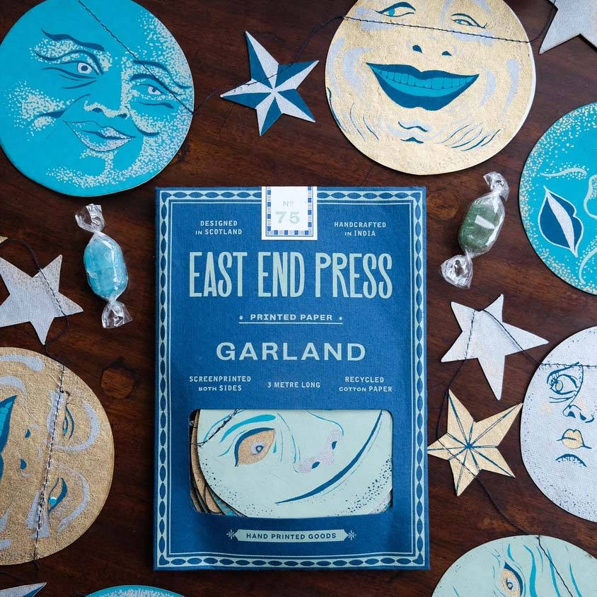 paper garland in blues and yellows of moon faces on a white background