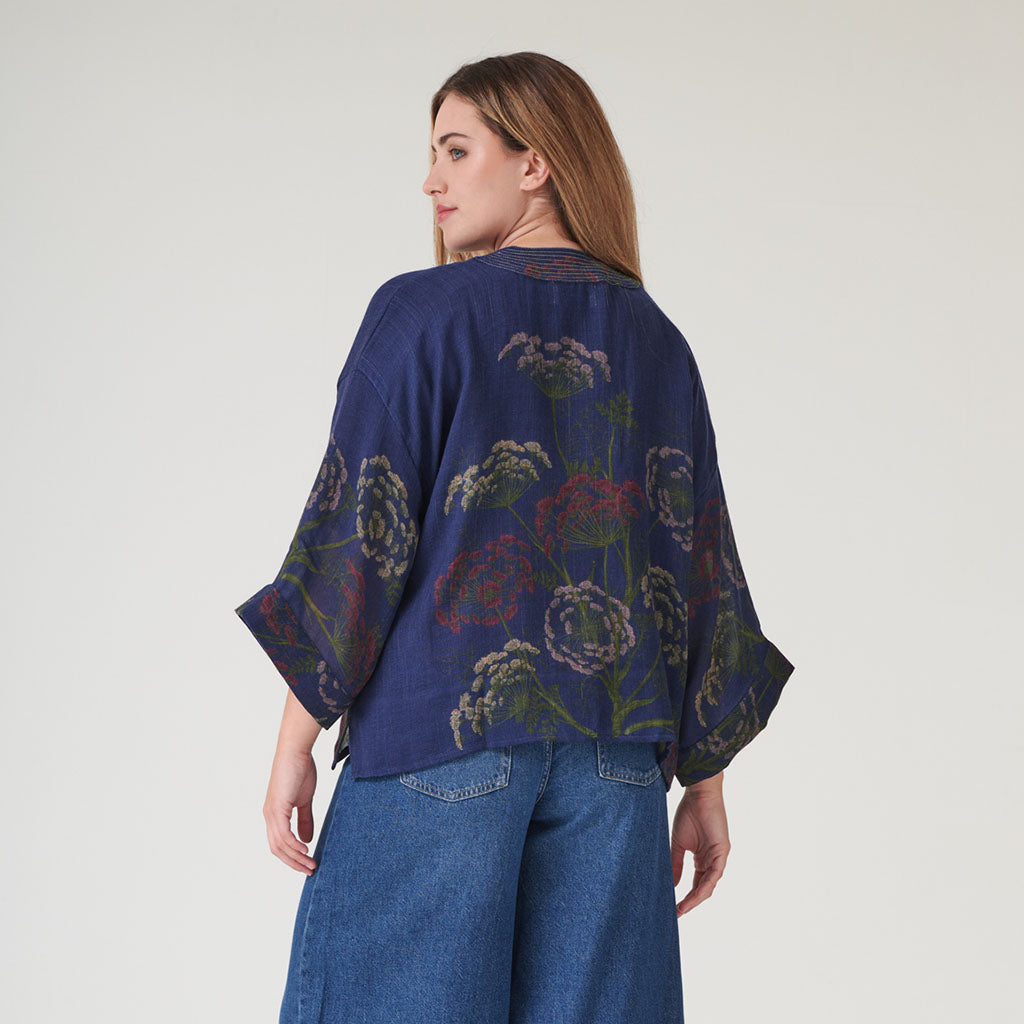 Woman wearing a blue floral patterned kimono-style wool jacket on a plain background