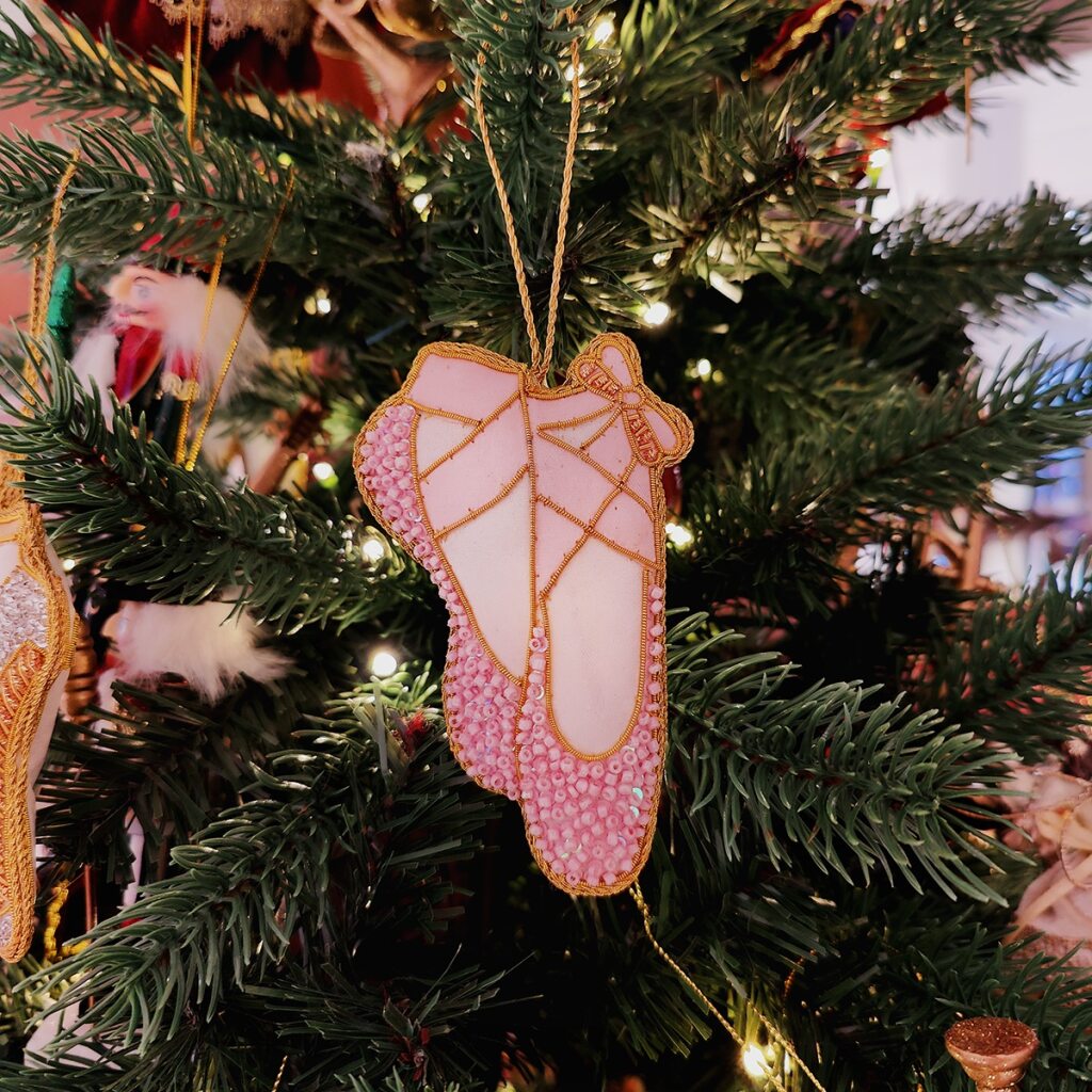 a pink beaded ballet shoe decoration  with gold trim on a white background