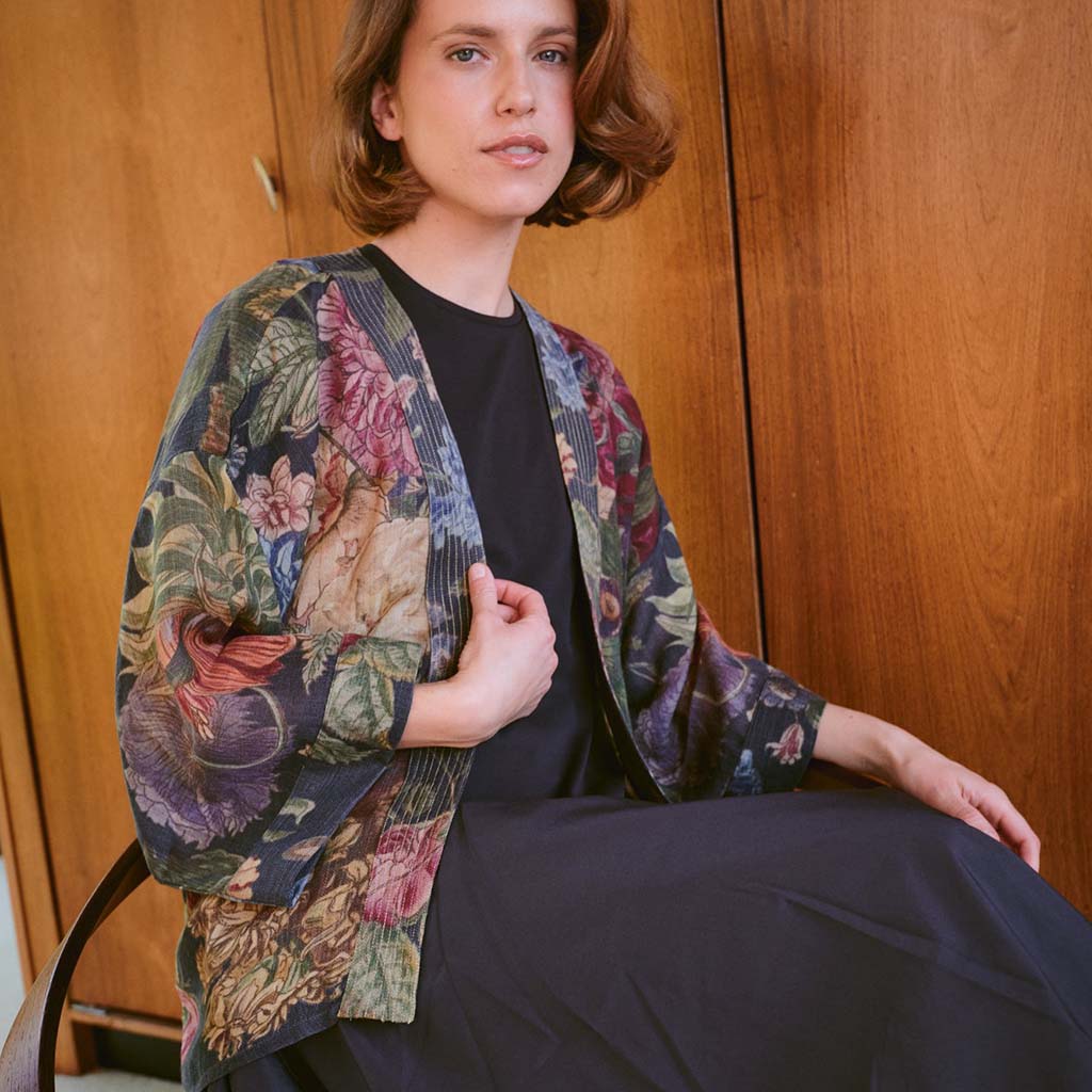 Woman wearing a floral kimono-style jacket against a wooden background