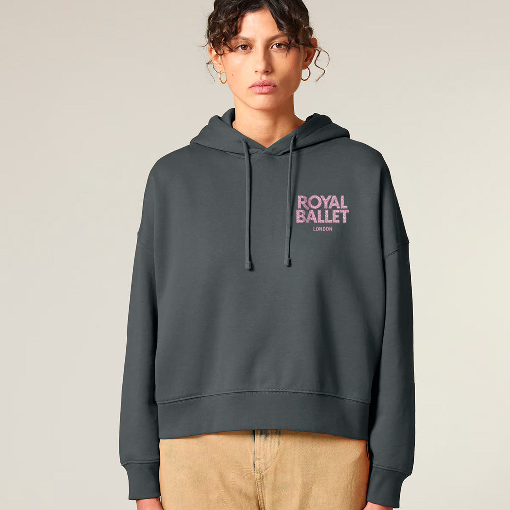 Person wearing a dark gray hoodie with 'Royal Ballet London' text on a beige background