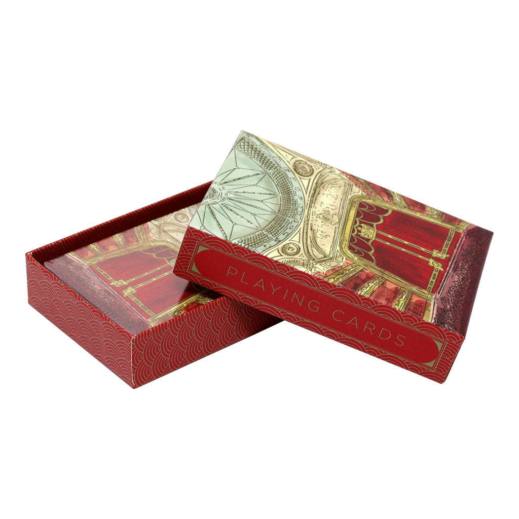 A set of Royal Ballet and Opera Auditorium Playing Cards. The box is open with the lid resting on the open box. The side of the lid and box are red with a geometric gold wave pattern. On the left side of the lid &quot;Playing Cards&quot; is written in gold. The top of the lid shows a painted style image of the Royal Ballet and Opera auditorium including the red and gold curtains and ornate blue domed ceiling. The inside of the box is obscured by the lid but we can see that the cards inside bear the same design. 
