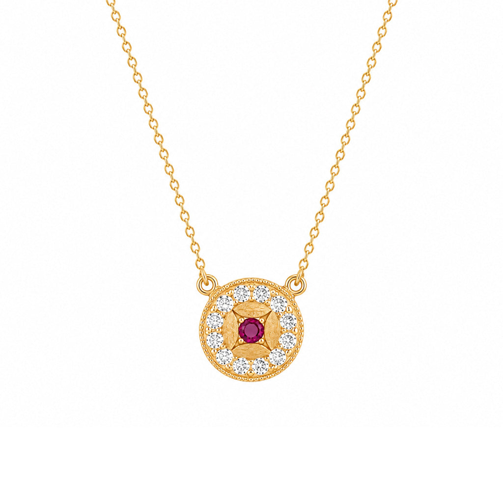 A gold pendant necklace featuring a circular design with a central red gemstone surrounded by small clear stones, suspended from a delicate gold chain on a white background.