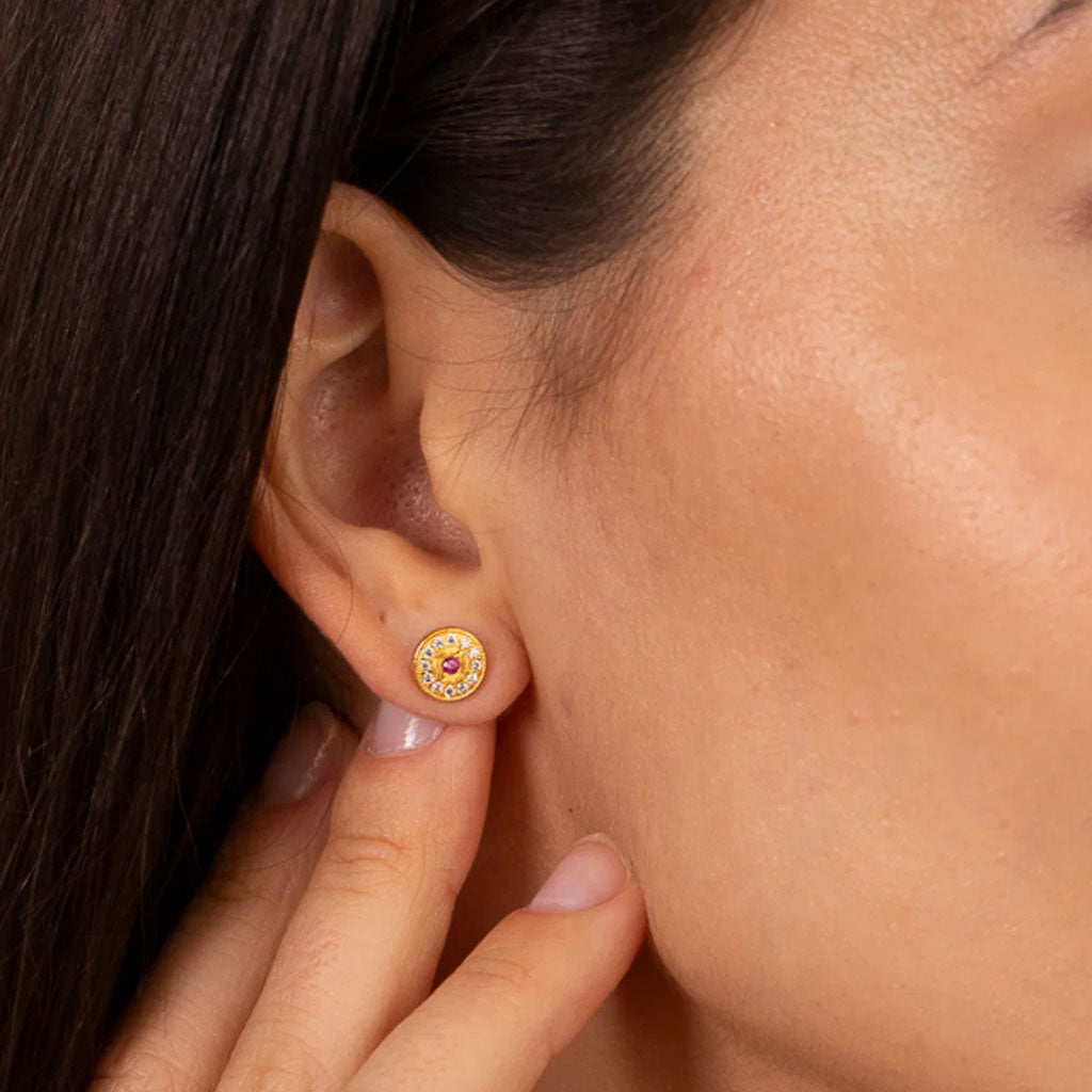 gold stud earrings with a red stone centre surrounded by diamonds on a white background