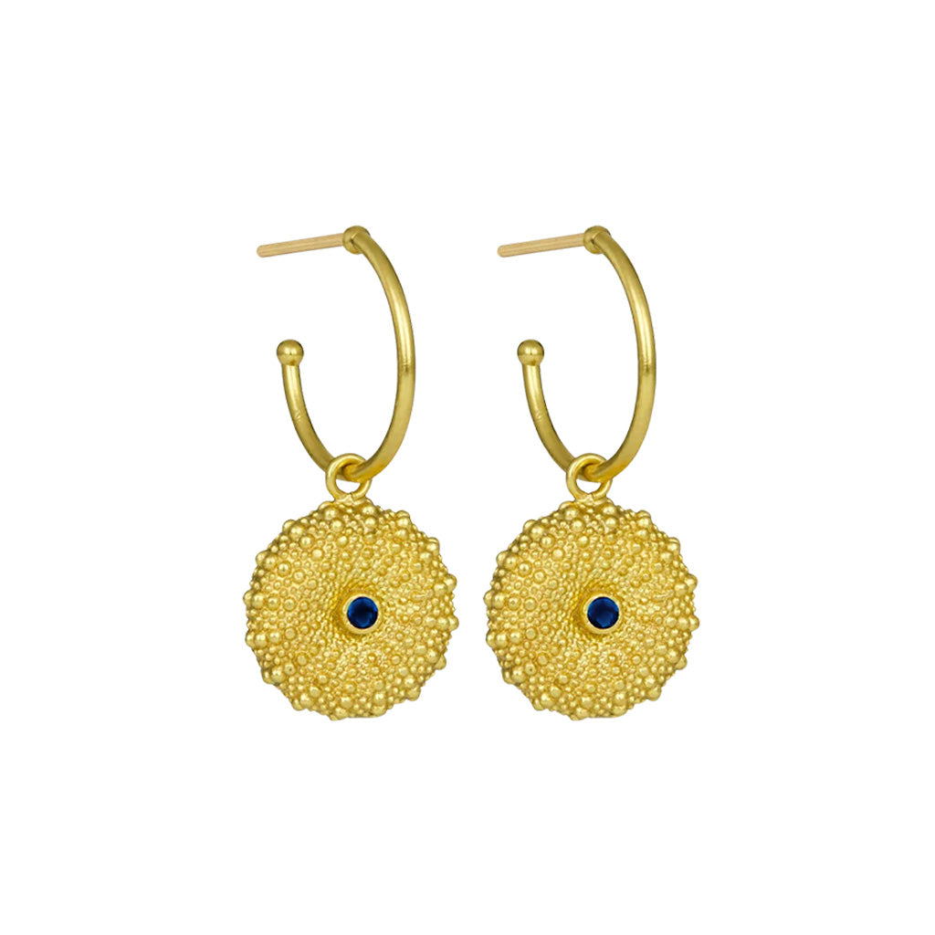 Gold plated brass hoop earrings with textured shall designs and dark blue gemstones on a white background