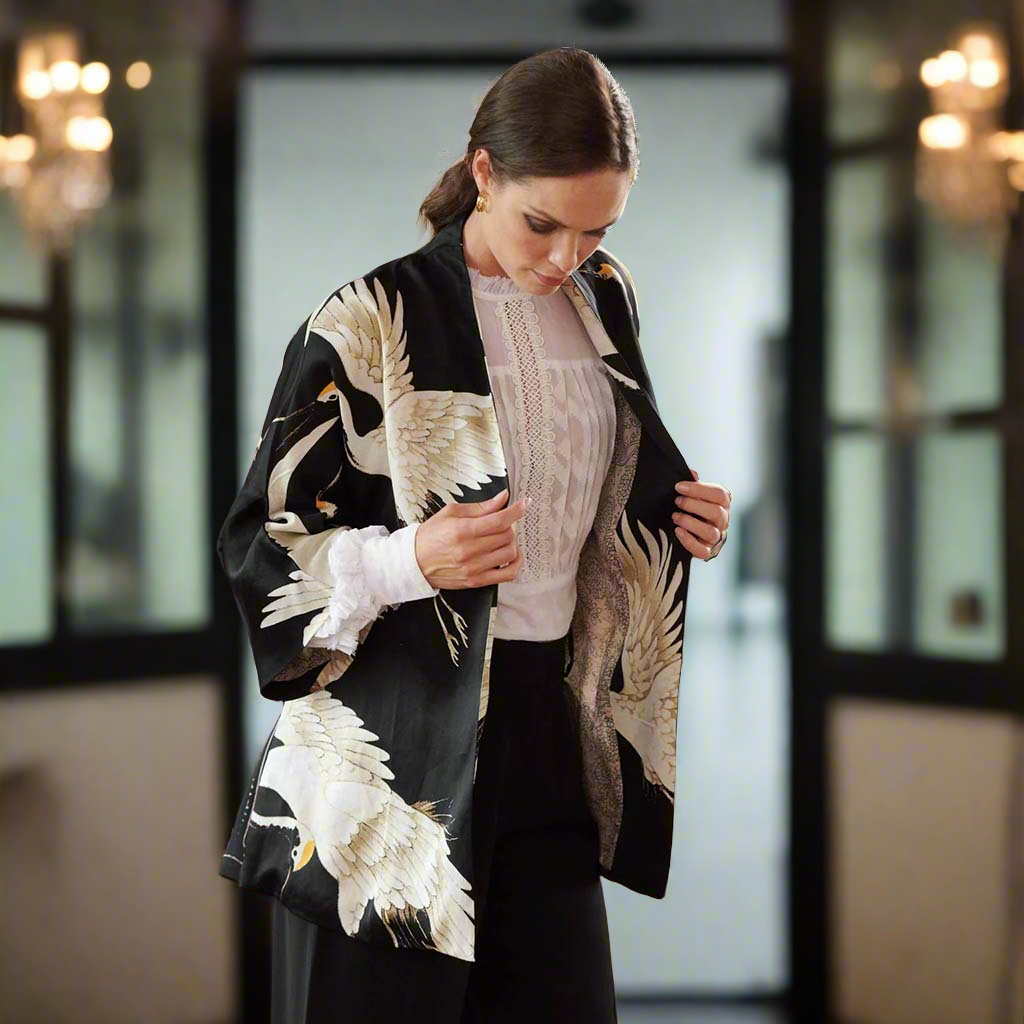 Model in Stork Black Wrap Jacket next to chandelier