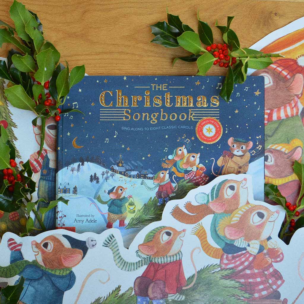 Children&#39;s book titled &#39;The Christmas Songbook&#39; surrounded by festive illustrated cut outs and holly.