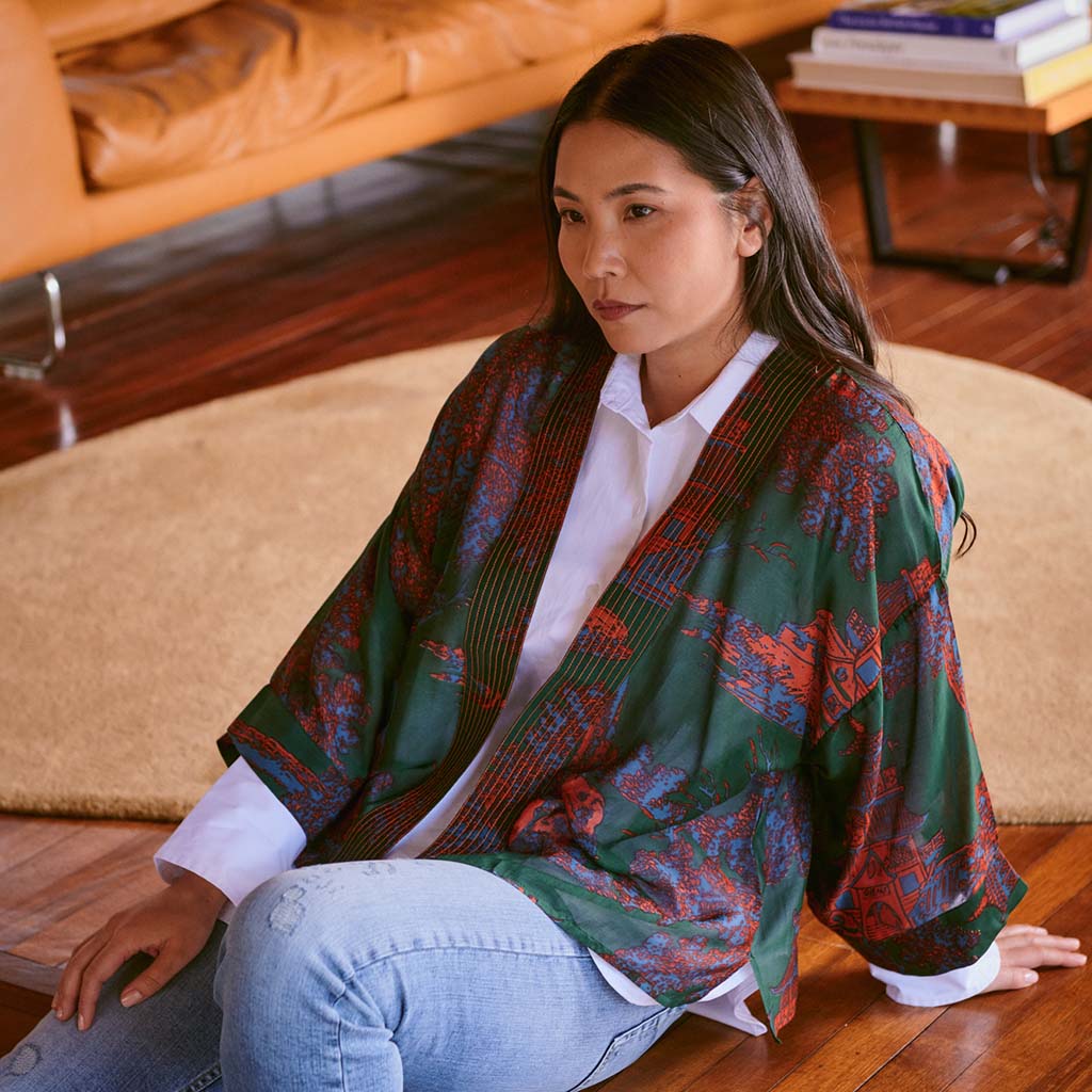 Green and orange pagoda patterned kimono on a white hanger against a white background