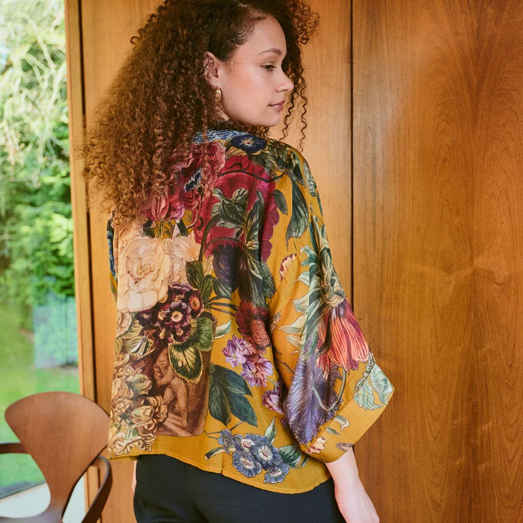 Gold floral design kimono style jacket on a hanger on a white background