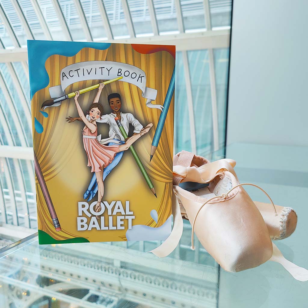 Royal Ballet activity book with ballet shoes on a reflective surface