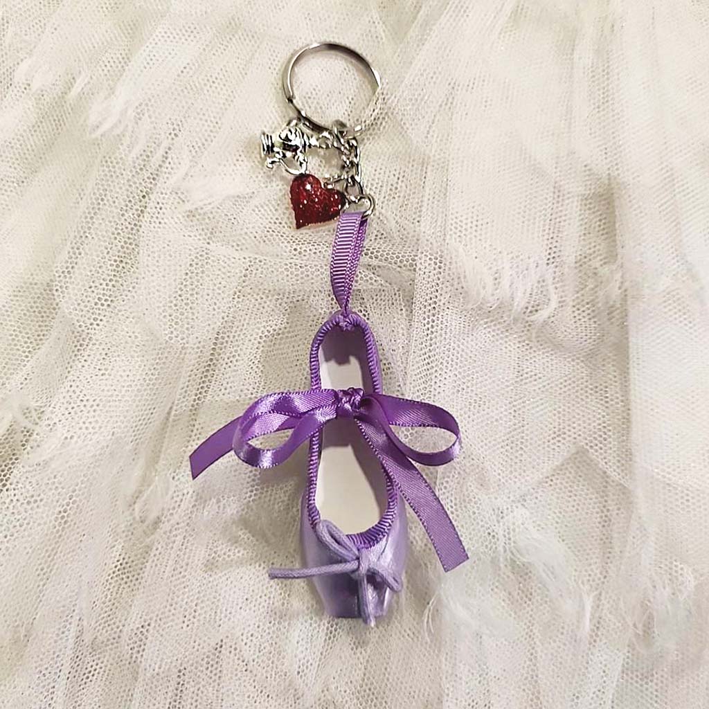 An Alice Limited Edition Ballet Shoe Keyring on a white lace background. 