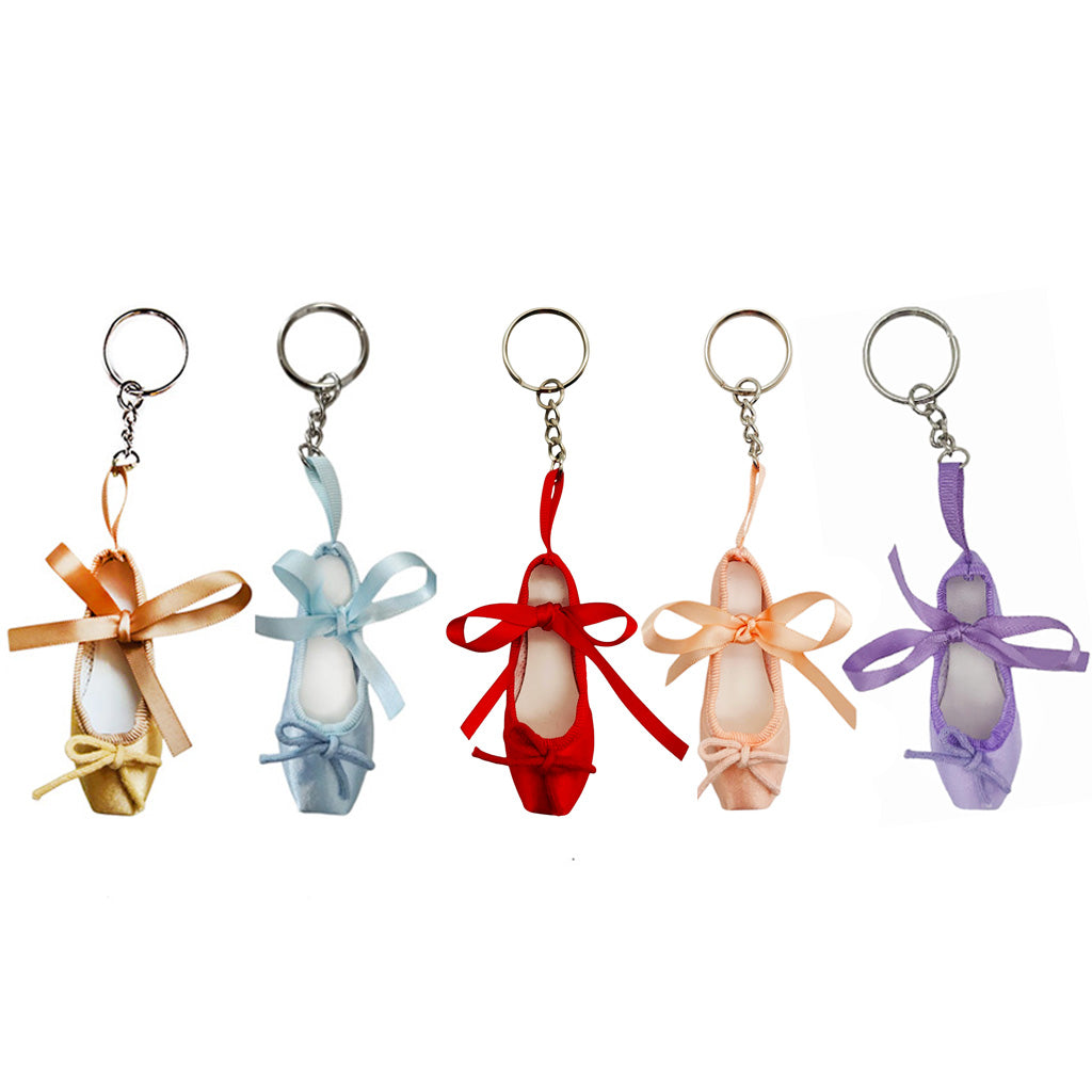 Five colourful ballet shoe keyrings with ribbons on a white background