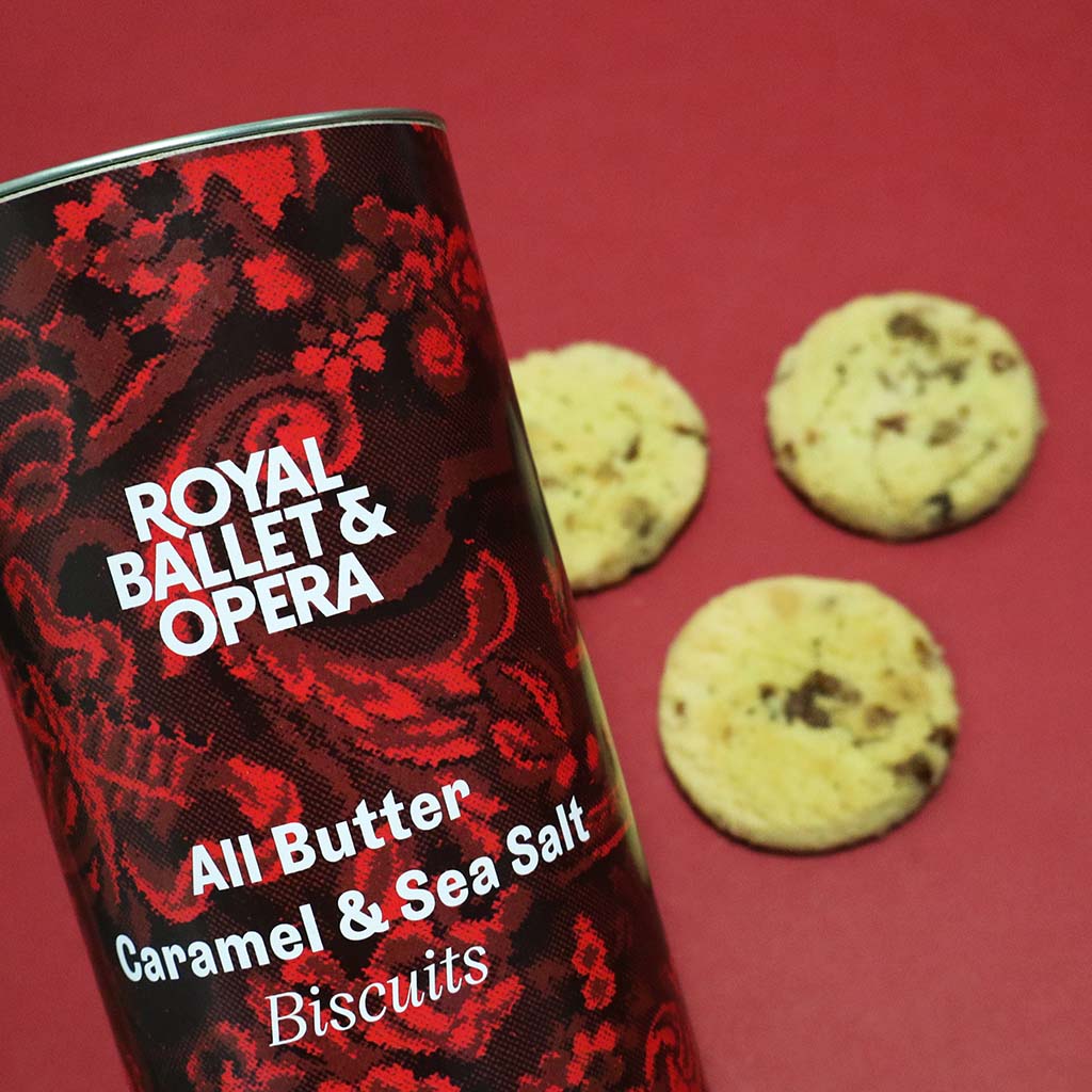 Cylindrical biscuit tin with red and black design and 'Royal Ballet & Opera' branding.
