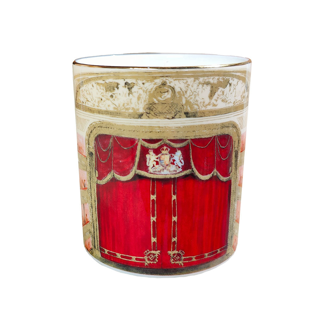 A ceramic candle featuring a printed design of a red velvet stage curtain with gold trim and a crest at the top, set against a plain white background.