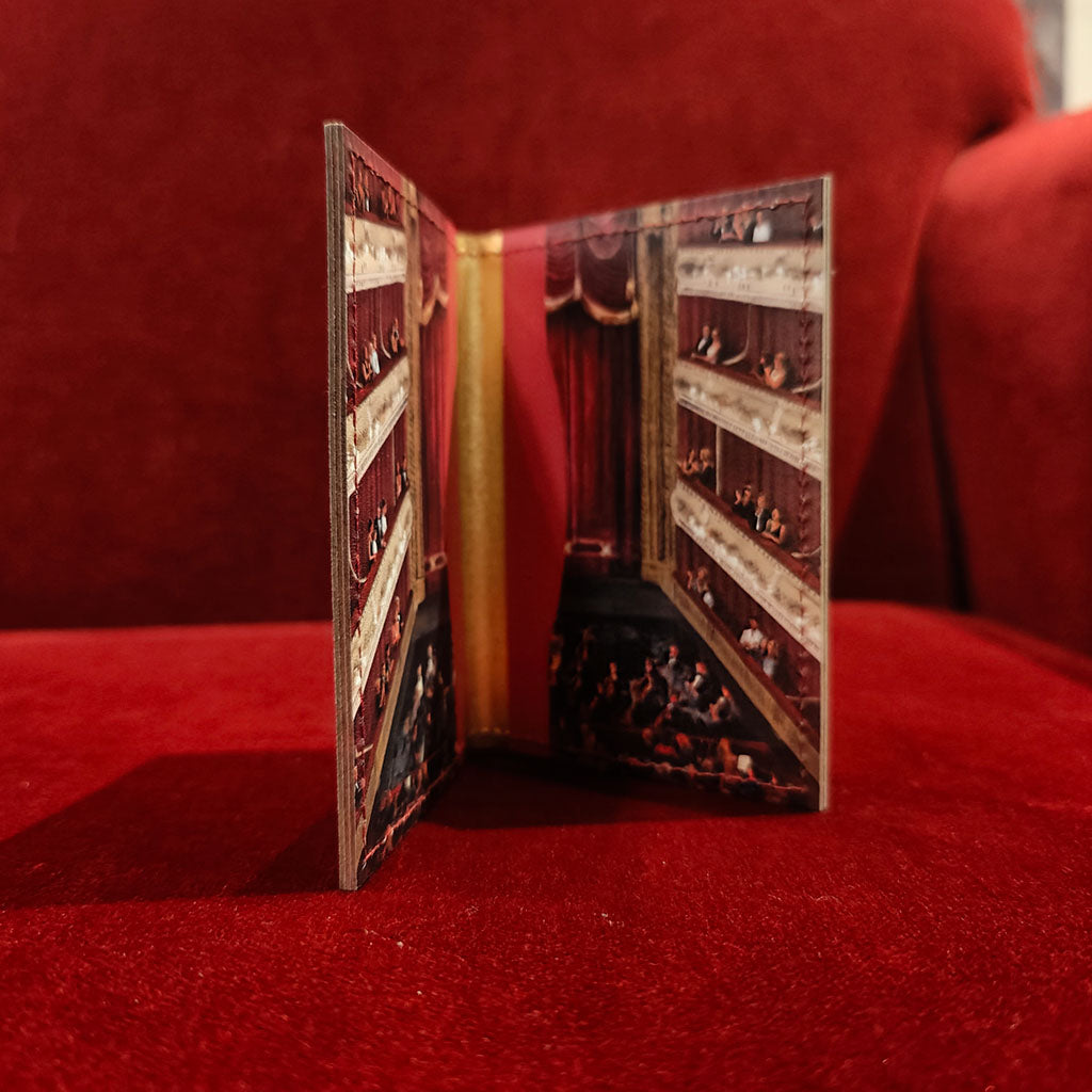 inside a leather card holder featuring a printed illustration of the auditorium at the royal opera house with people in the balconies shown on a red velvet surface