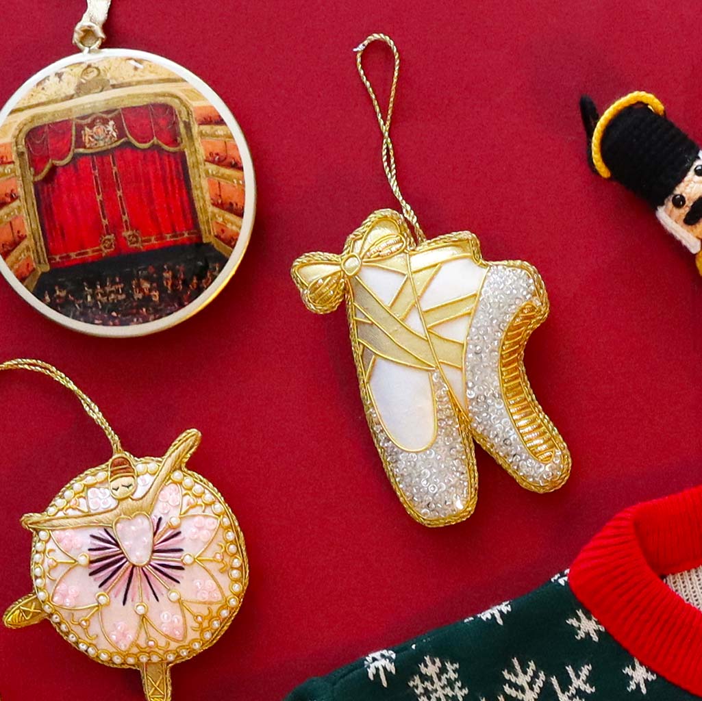 Decorative ballet shoe decoration with gold and silver details on a white background