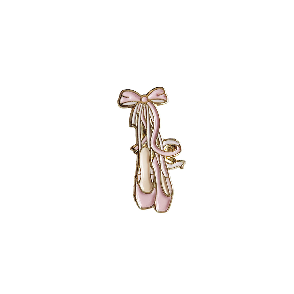 Pin with pink pointe ballet shoes and a bow on a white background