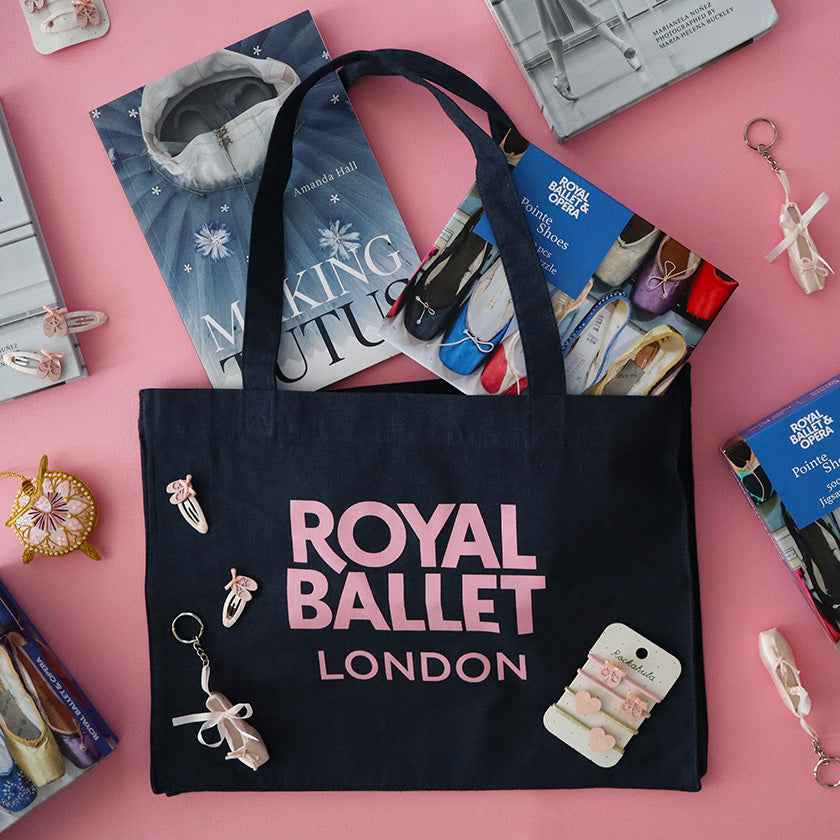 Denim tote bag with 'Royal Ballet London' text on a pink background surrounded by ballet-themed items.