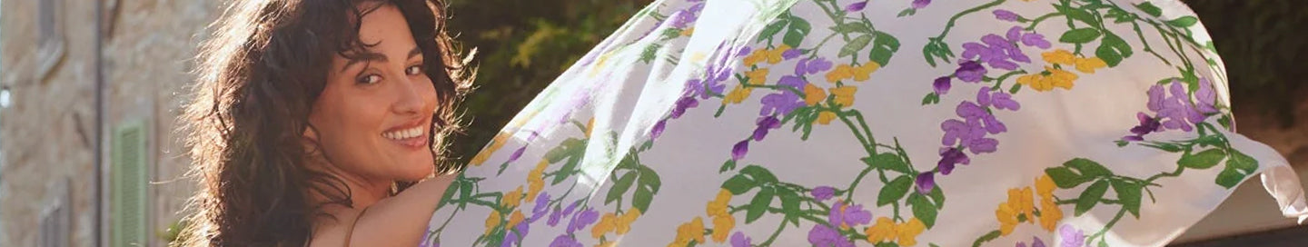 Woman holding a floral-patterned white scarf outdoors