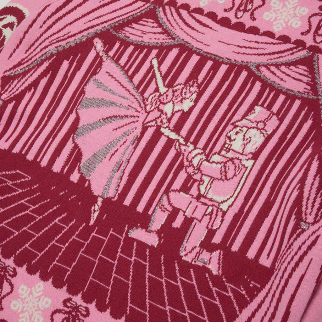 A close-up of a pink and burgundy  and silver woven textile featuring a stage  curtains, with Barbie and the Nutcracker performing on stage.