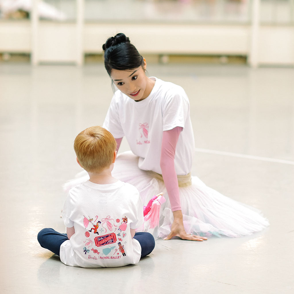 A white short-sleeve crewneck t-shirt featuring a pink graphic of a ballet pointe with a bow and the text 'Barbie ROYAL BALLET' printed on the chest.