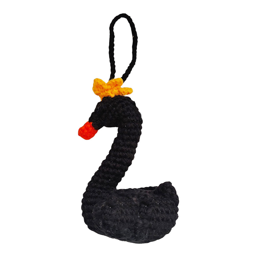 swan crochet decoration made of black cotton with an orange beak and yellow crown on a white background
