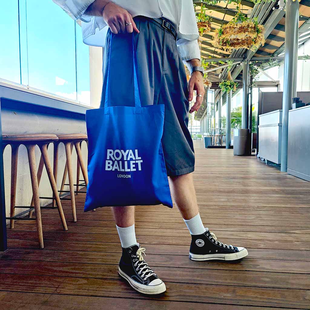 Person holding a blue &#39;Royal Ballet London&#39; tote bag on the RBO terrace.