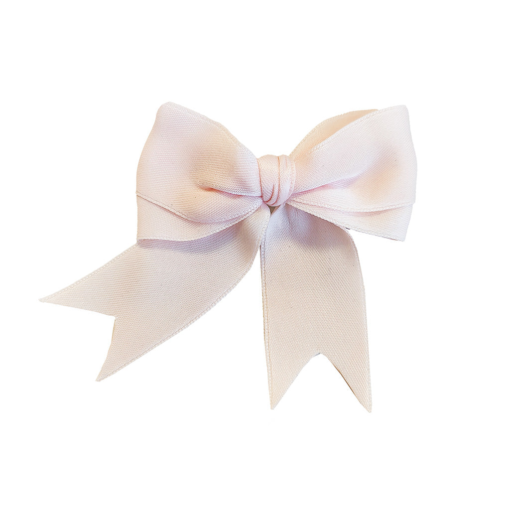 A pale blush pink satin ballet bow hairclip with two long ribbon tails, photographed against a solid white background.