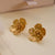Pair of gold flower-shaped buttercup earrings on a white background
