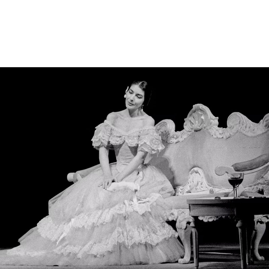 Print featuring Maria Callas as Violetta sitting one a large ornate chair onstage