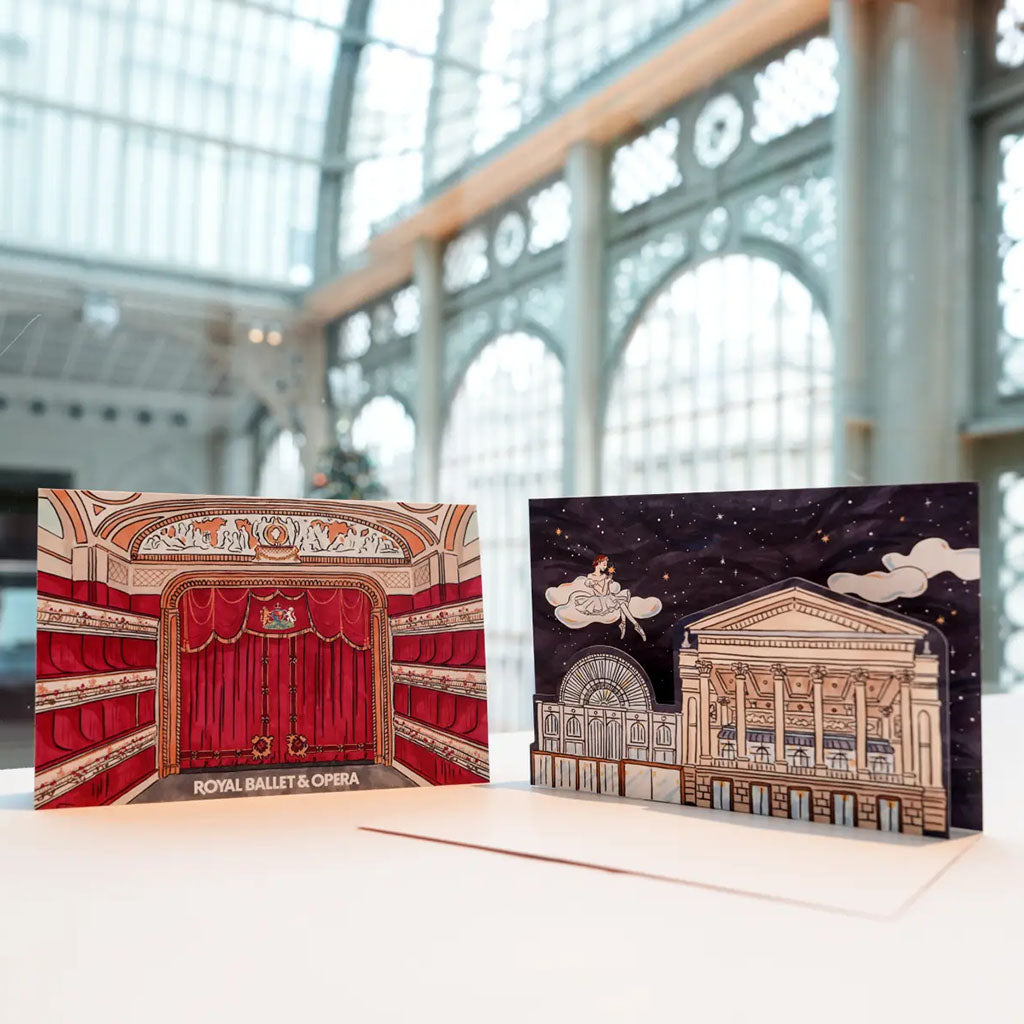 Foxco greeting cards with architectural designs, front labelled 'Royal Ballet &amp; Opera' and the inside with a pop up exterior building and cloud design, displayed against a blurred interior background.