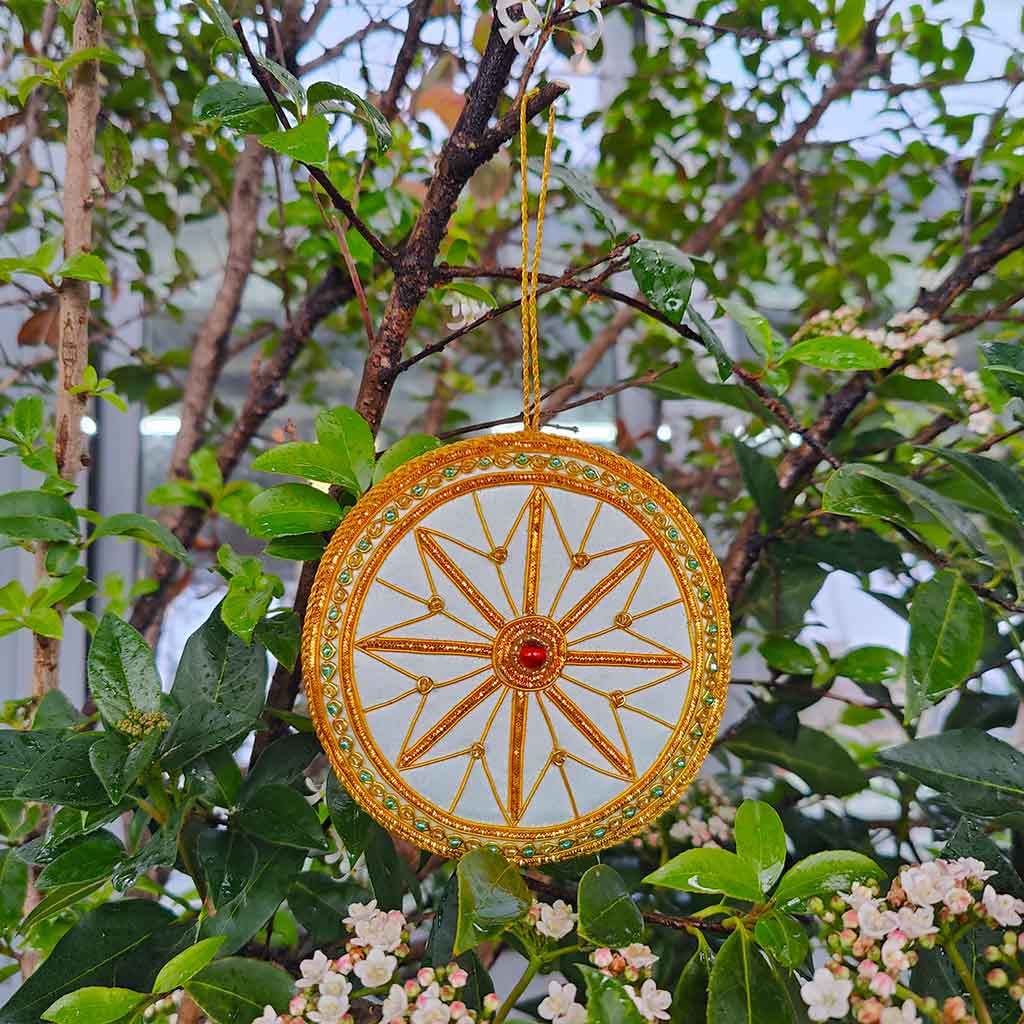 Decorative circular decoration inspired by the auditorium ceiling  at the RBO with gold  and blue detailing and a red gemstone on a white background