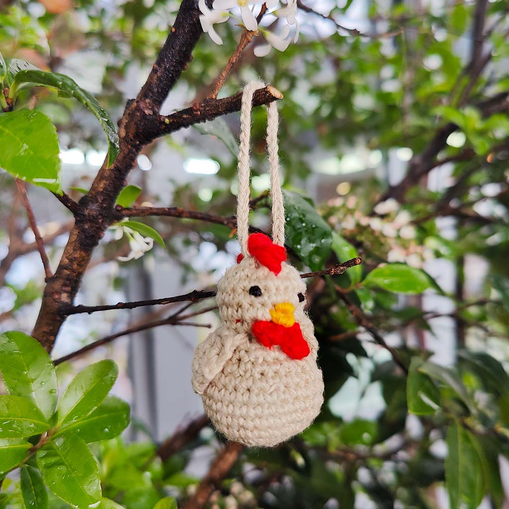 crochet chicken decoration hanging on a tree branch