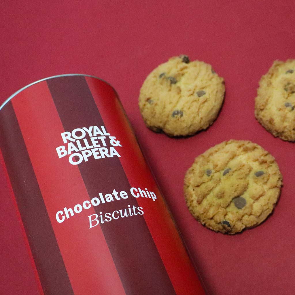 Chocolate chip biscuits next to a &#39;Royal Ballet &amp; Opera&#39; branded tin on a red background