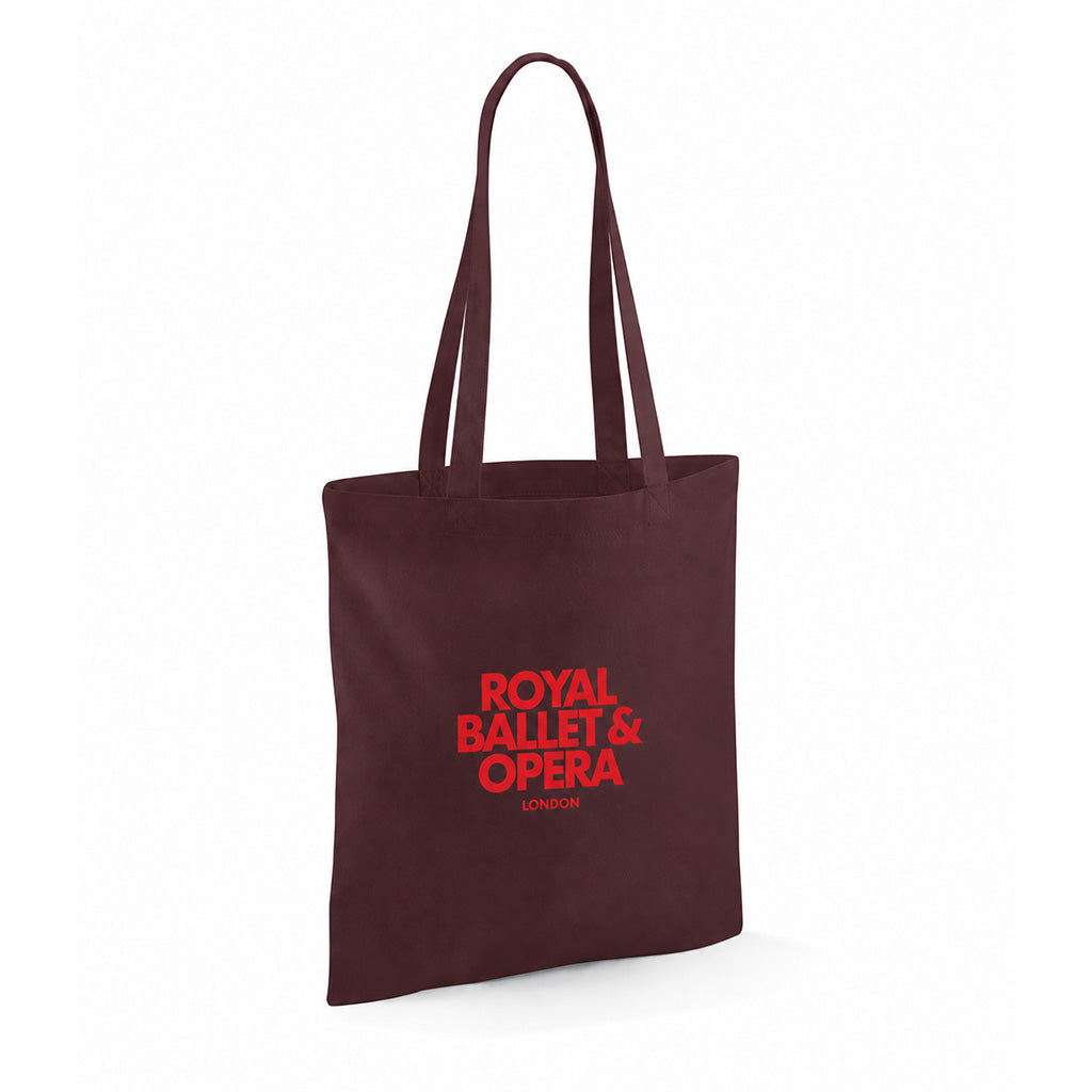 A dark chocolate cotton tote bag with  handles, featuring the text 'ROYAL BALLET &amp; OPERA LONDON' printed in red on the front, set against a plain white background.
